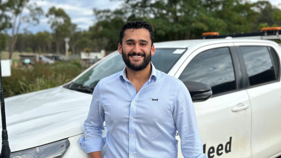 Leed - Seth Do Bono is standing next to a Leed branded vehicle, holding a white hard hat.