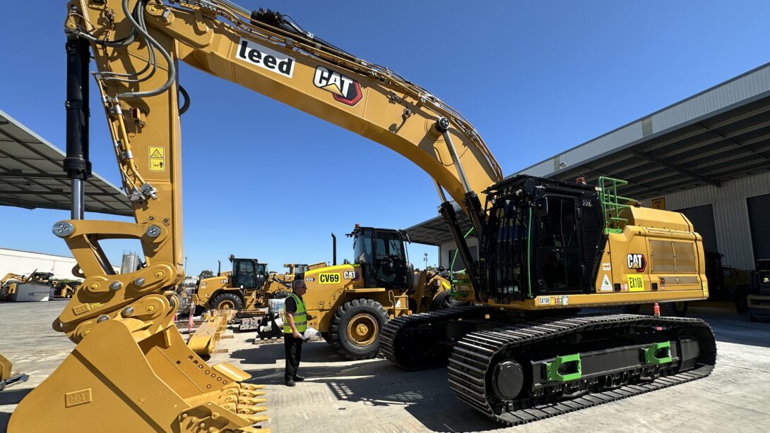 Leed - This yellow 50 tonne excavator, situated in Leed's yard with a worker dwarfed by its size, has the latest safety features.